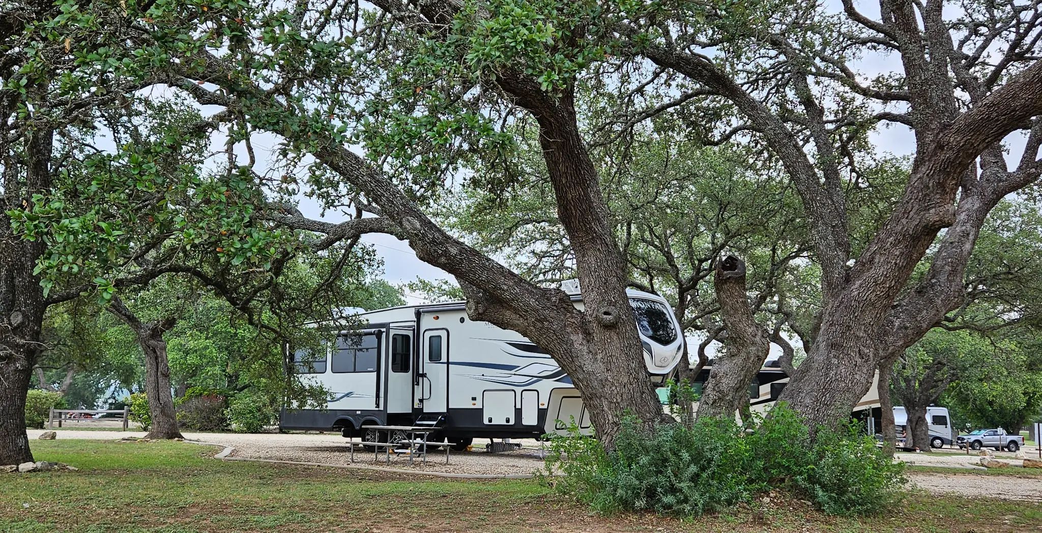 RV parked under mature oak trees at Bending Oaks Ranch - showcasing our family-owned Texas Hill Country resort