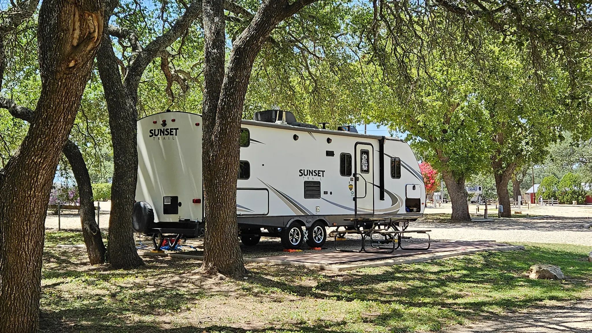 Sunset Trail RV parked under mature oak trees at Bending Oaks Ranch